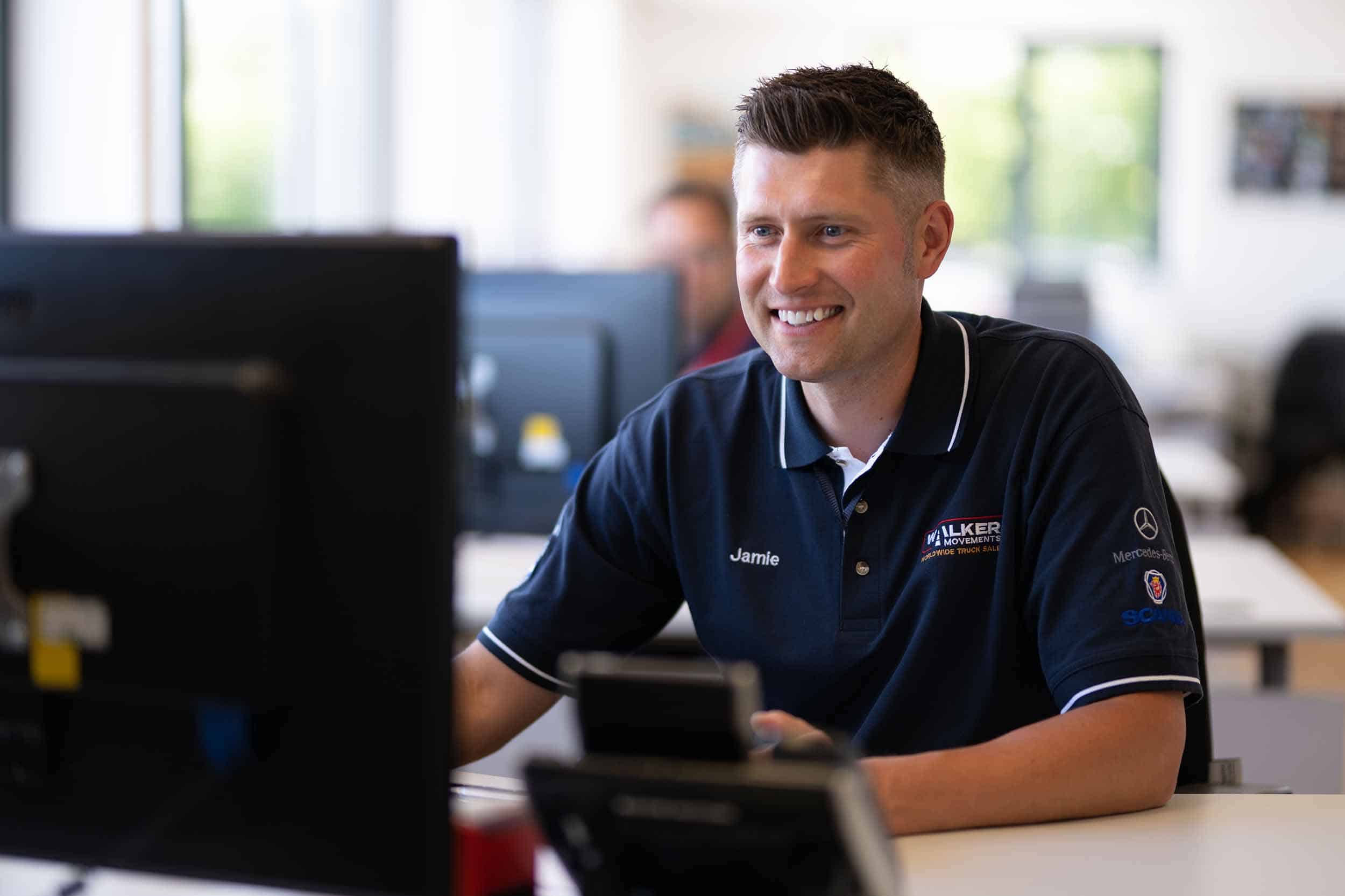 a sales person smiles whilst looking at a computer